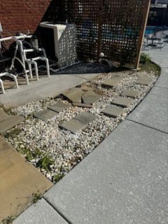 A Concrete Walkway Surrounded by Gravel and a Wooden Fence