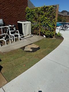 A Lawn With a Concrete Walkway and a Brick Building in the Background