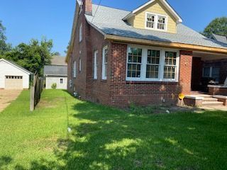 A Large Brick House With a Lot of Windows is Sitting on Top of a Lush Green Lawn