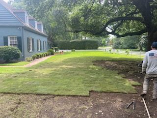 A Man is Standing in Front of a Large Lawn in Front of a House