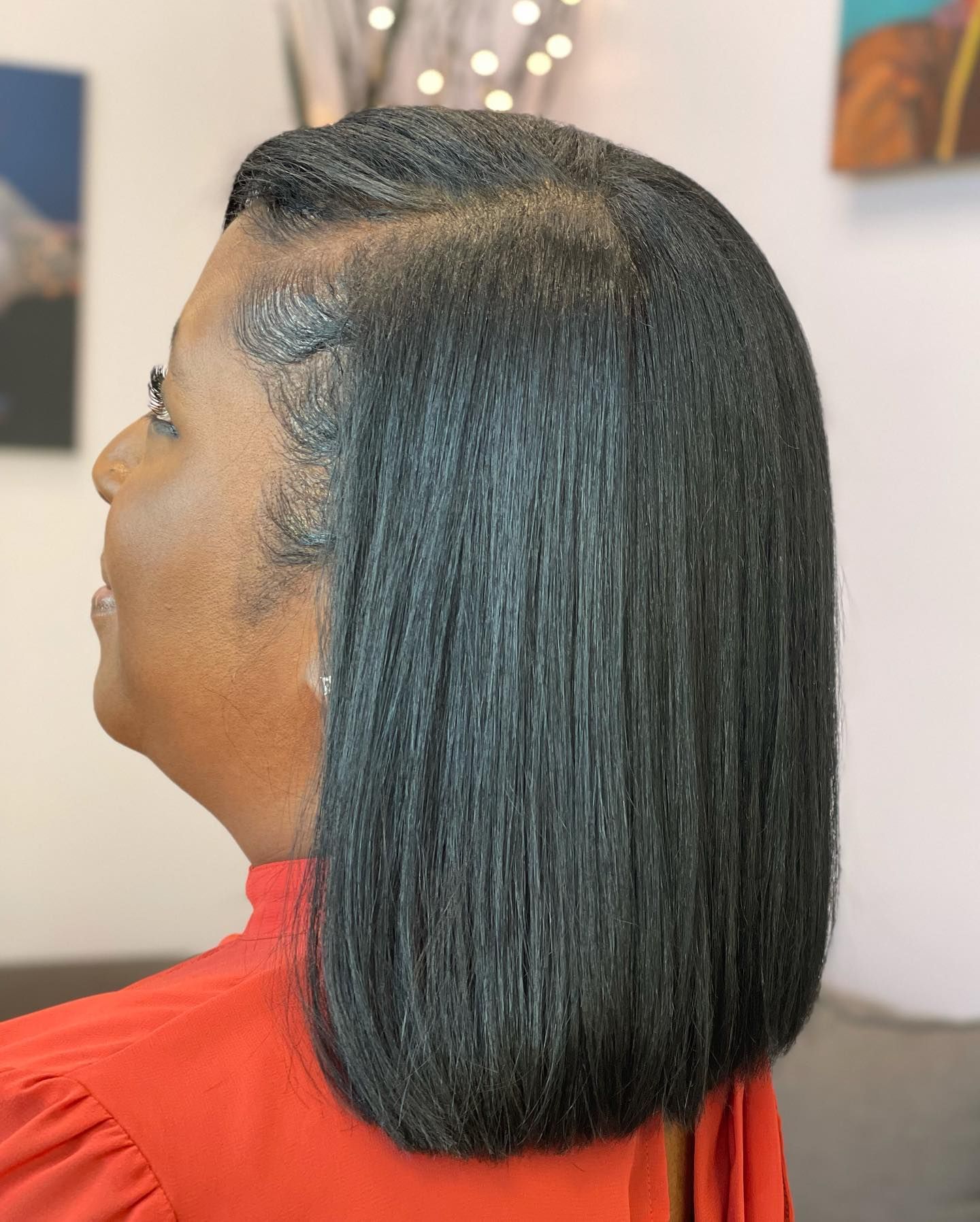 Woman with straight, dark hair, side profile, wearing an orange top.