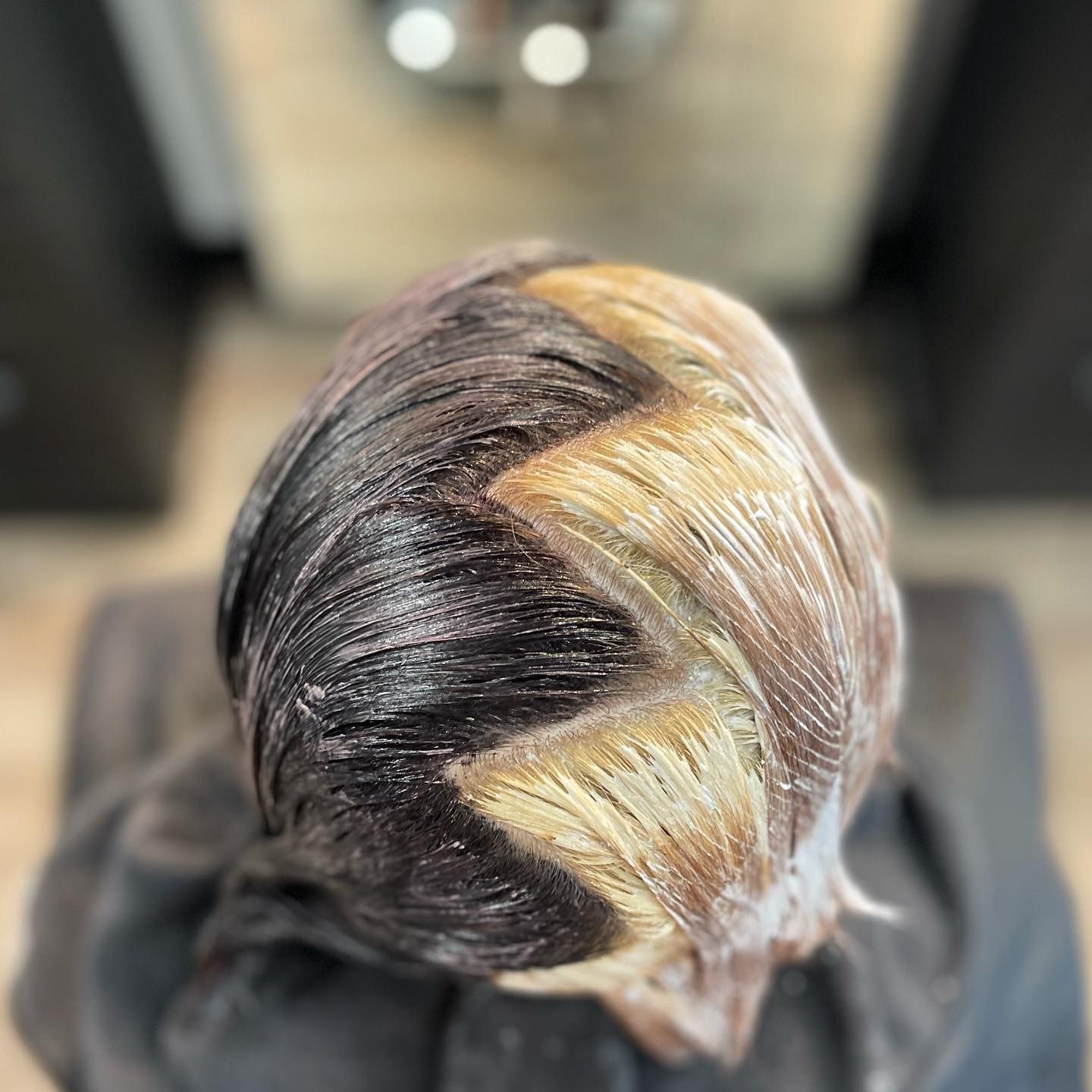 Hair with bleach applied in a zig-zag pattern, black and blonde sections.