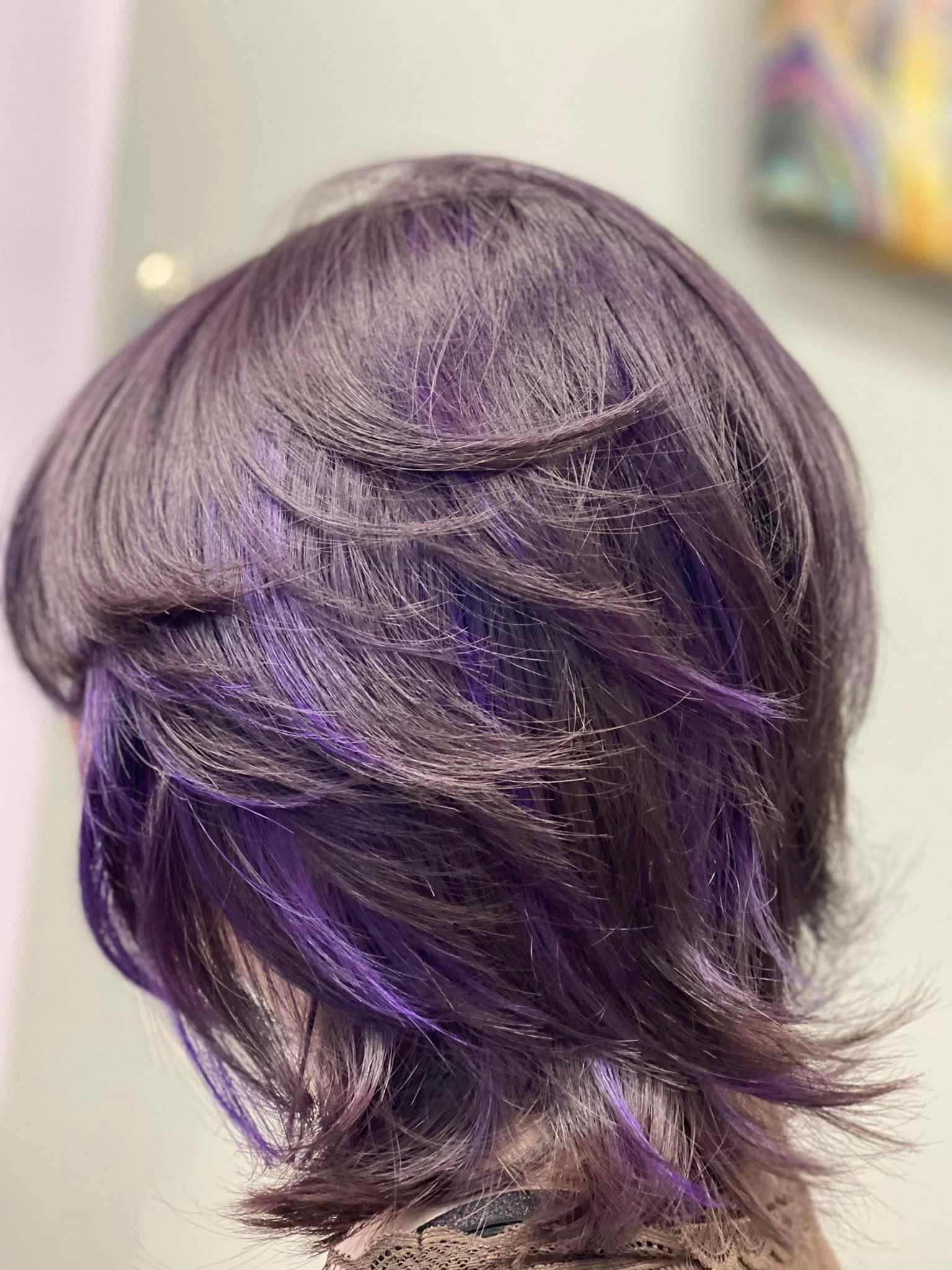 Close-up of layered dark purple hair with streaks of bright purple highlights.