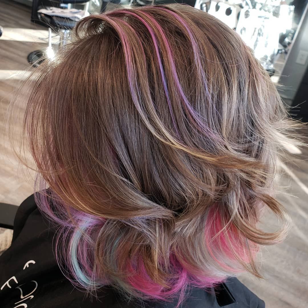 Brown hair with pastel pink, purple, and blue highlights, styled in a layered cut.