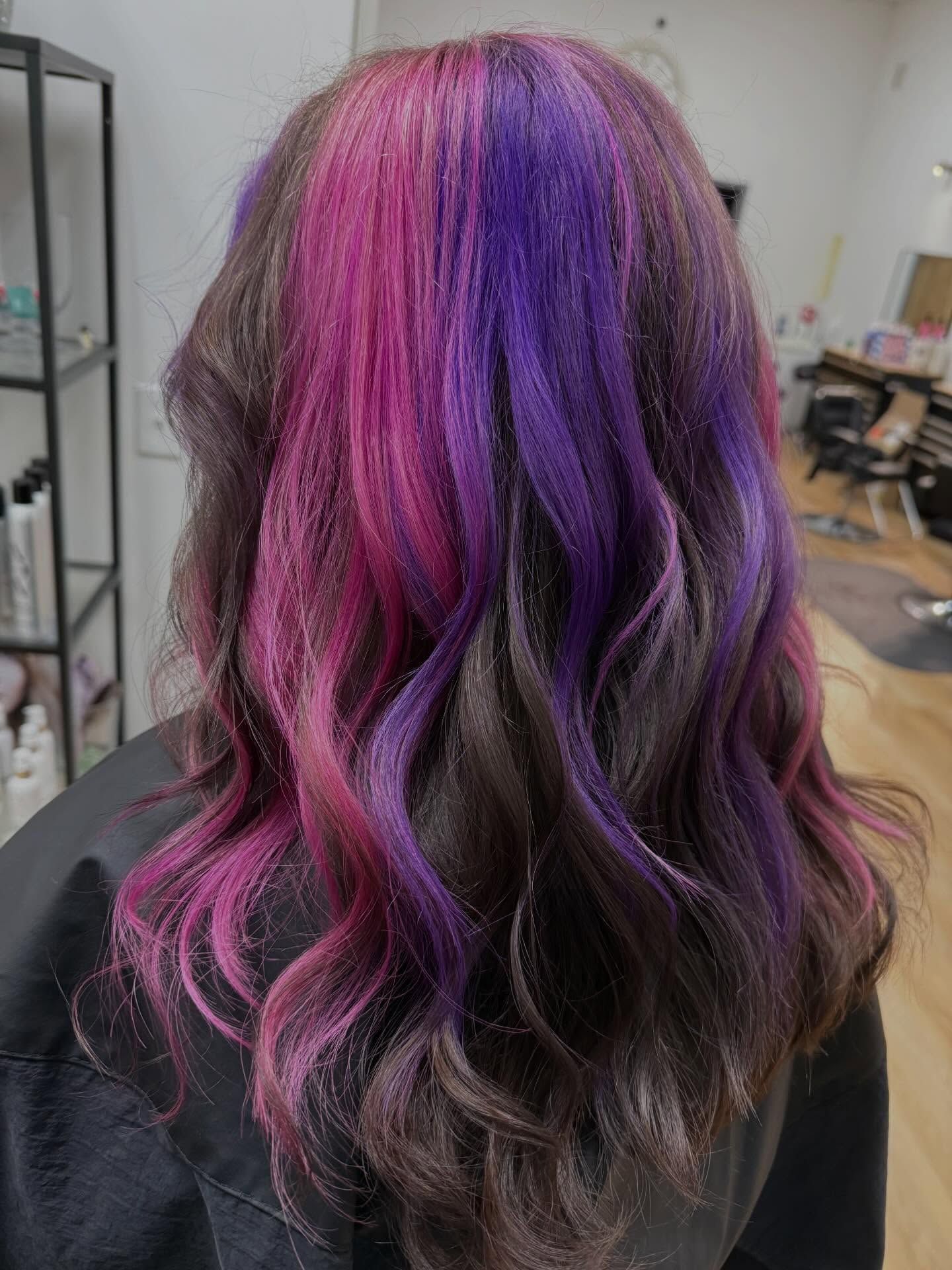 Woman with dark brown hair, vibrant pink and purple highlights.
