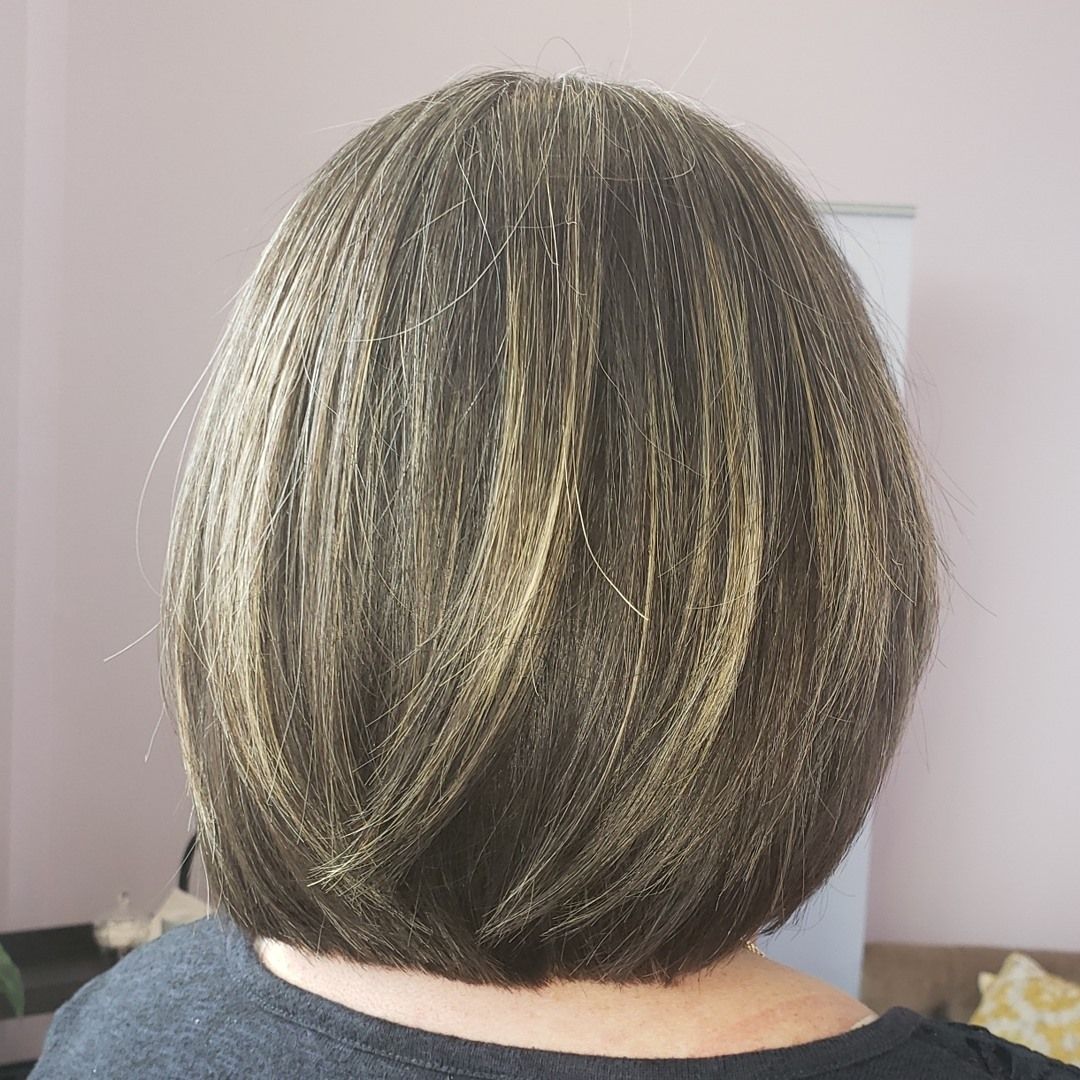 Back of a person's head with short, layered brown hair with blonde highlights.