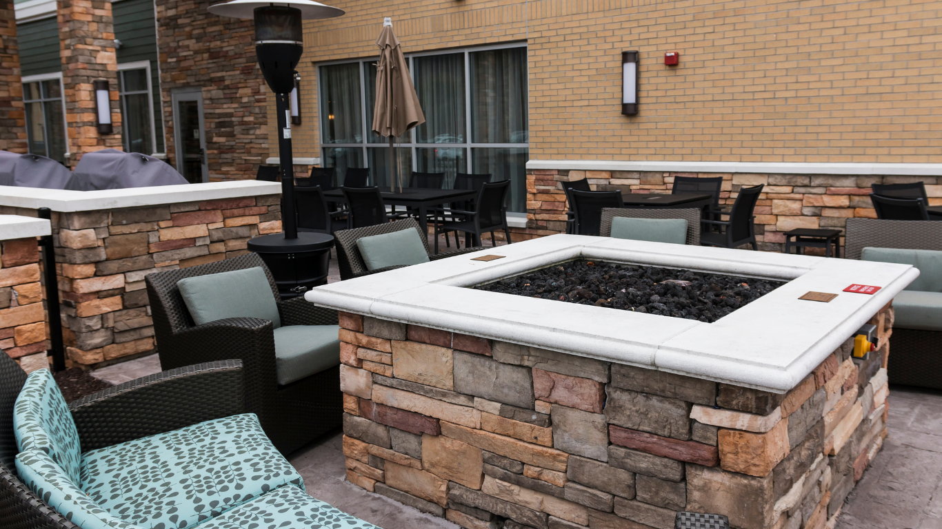 Patio seating area with stone fire pit, chairs, tables, and a patio heater.