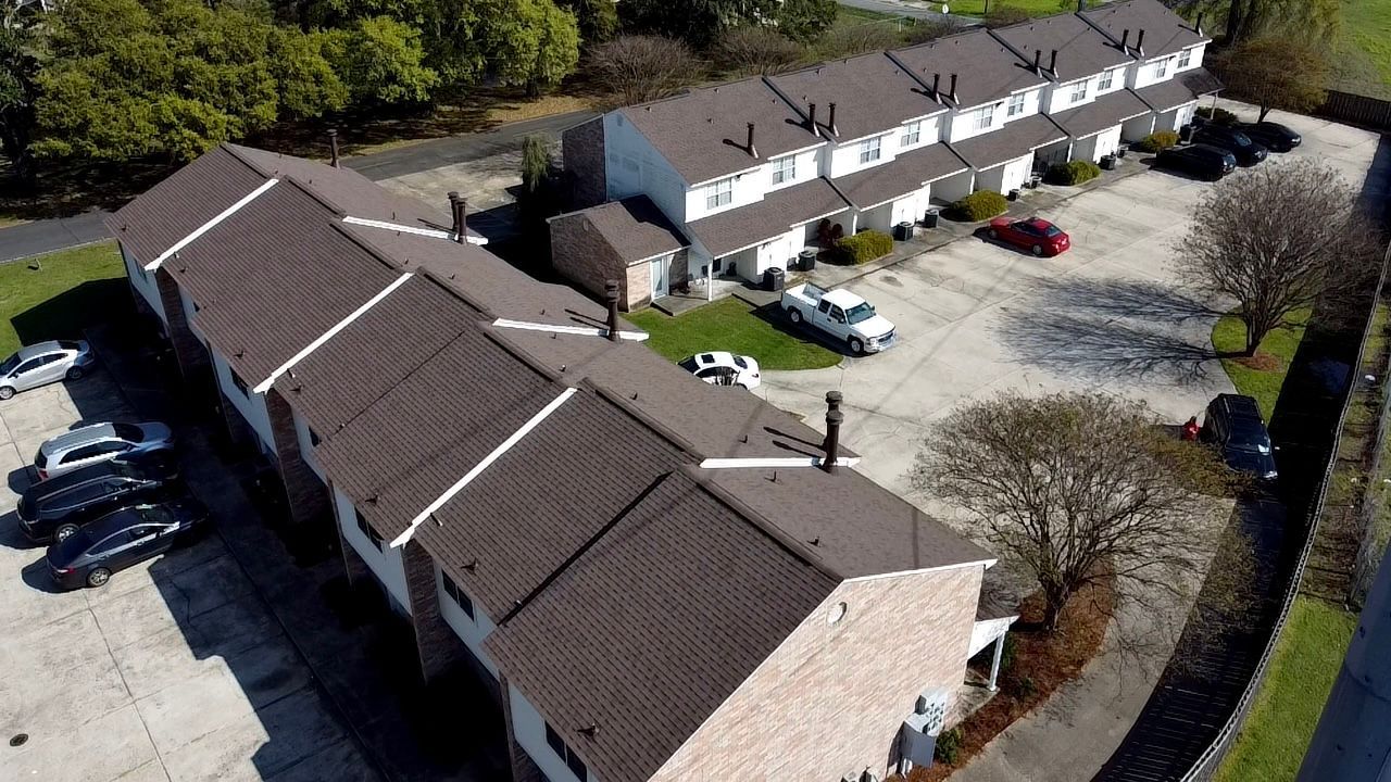 An aerial view of a row of houses with cars parked in front of them.