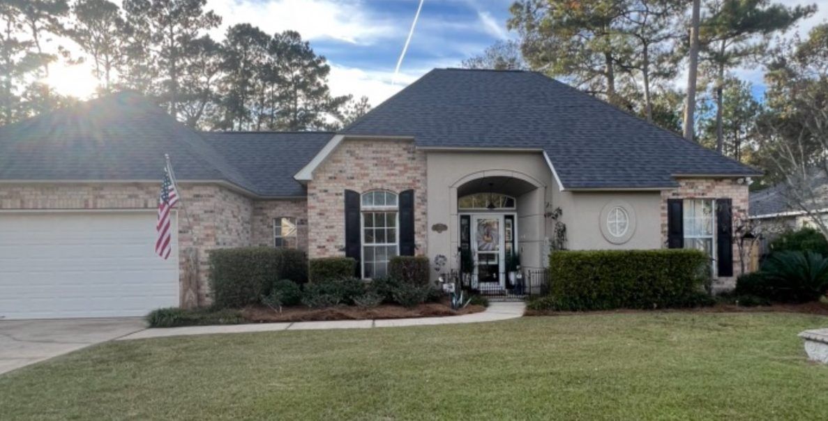 A large brick house with a black roof and a white garage door.