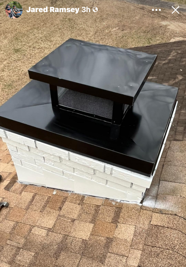 A black chimney cap is sitting on top of a white brick chimney.