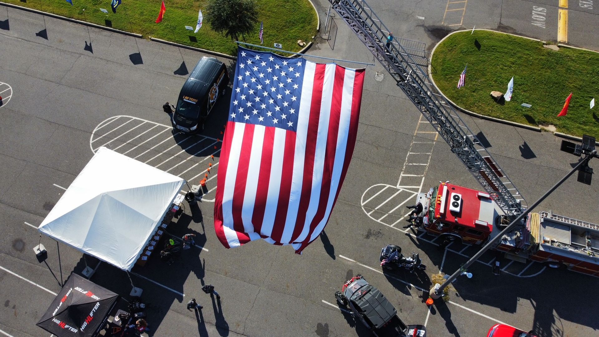 An aerial view of a large american flag flying over a parking lot.