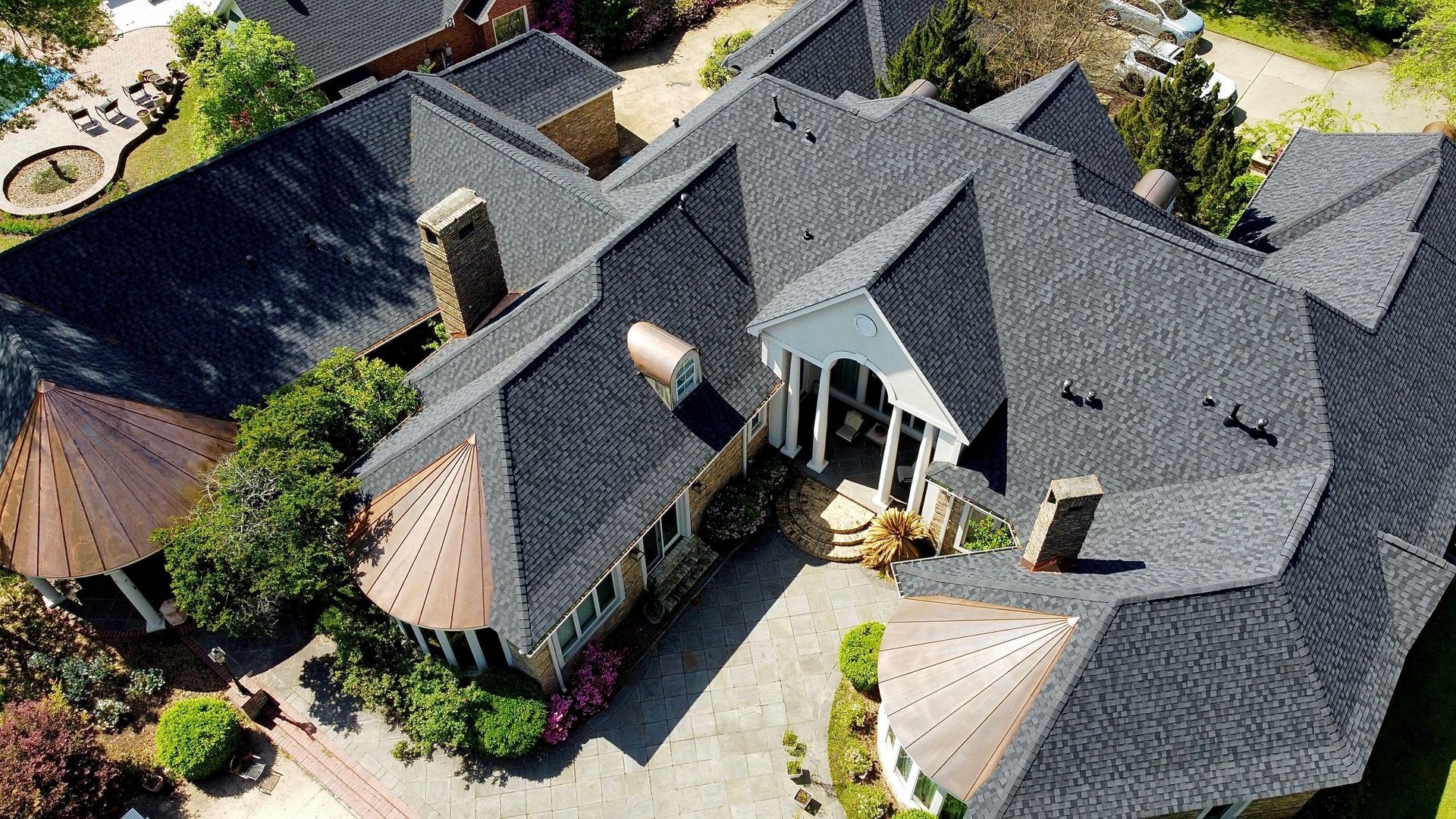 An aerial view of a large house with a black roof.