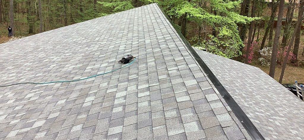A close up of a roof with a hole in it and trees in the background.