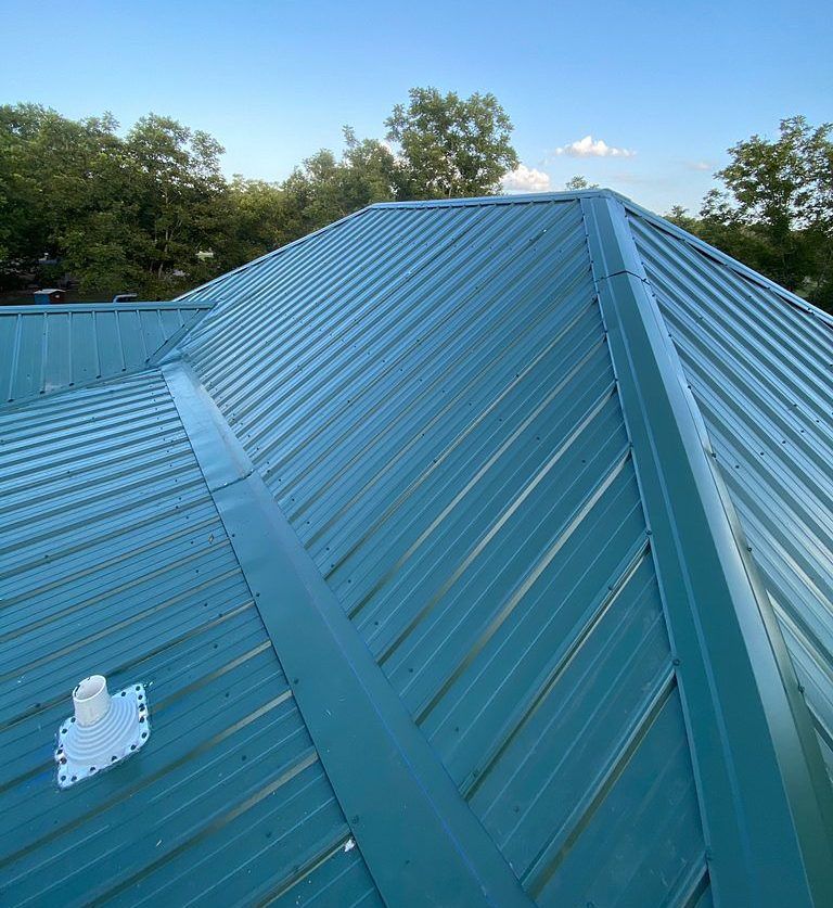 A close up of a blue metal roof with trees in the background