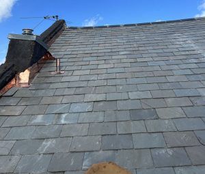 A roof with a chimney on top of it and a blue sky in the background.