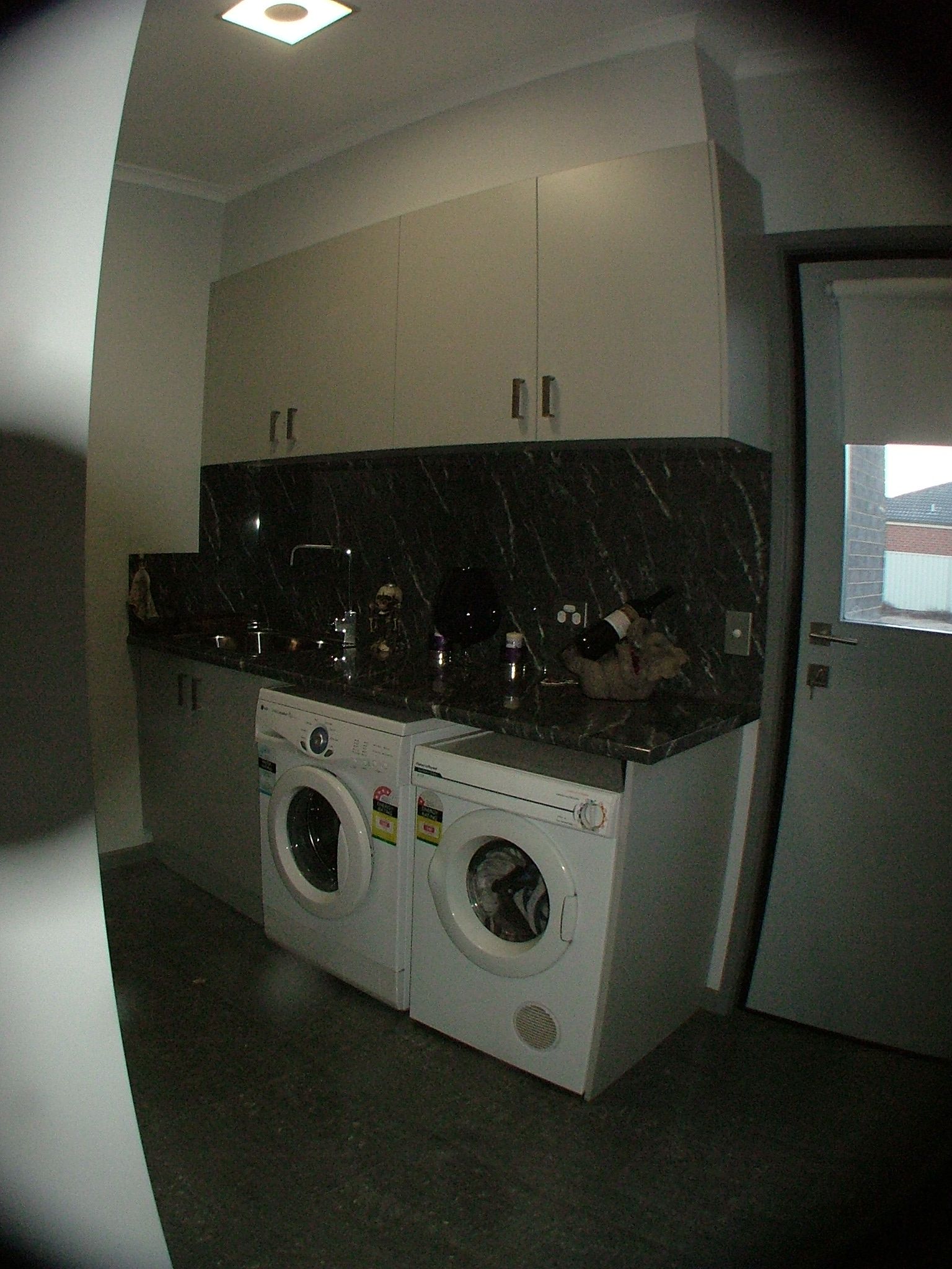 A laundry room with a washing machine and dryer, countertop, cabinets, and a closed door. The floor is dark wood.