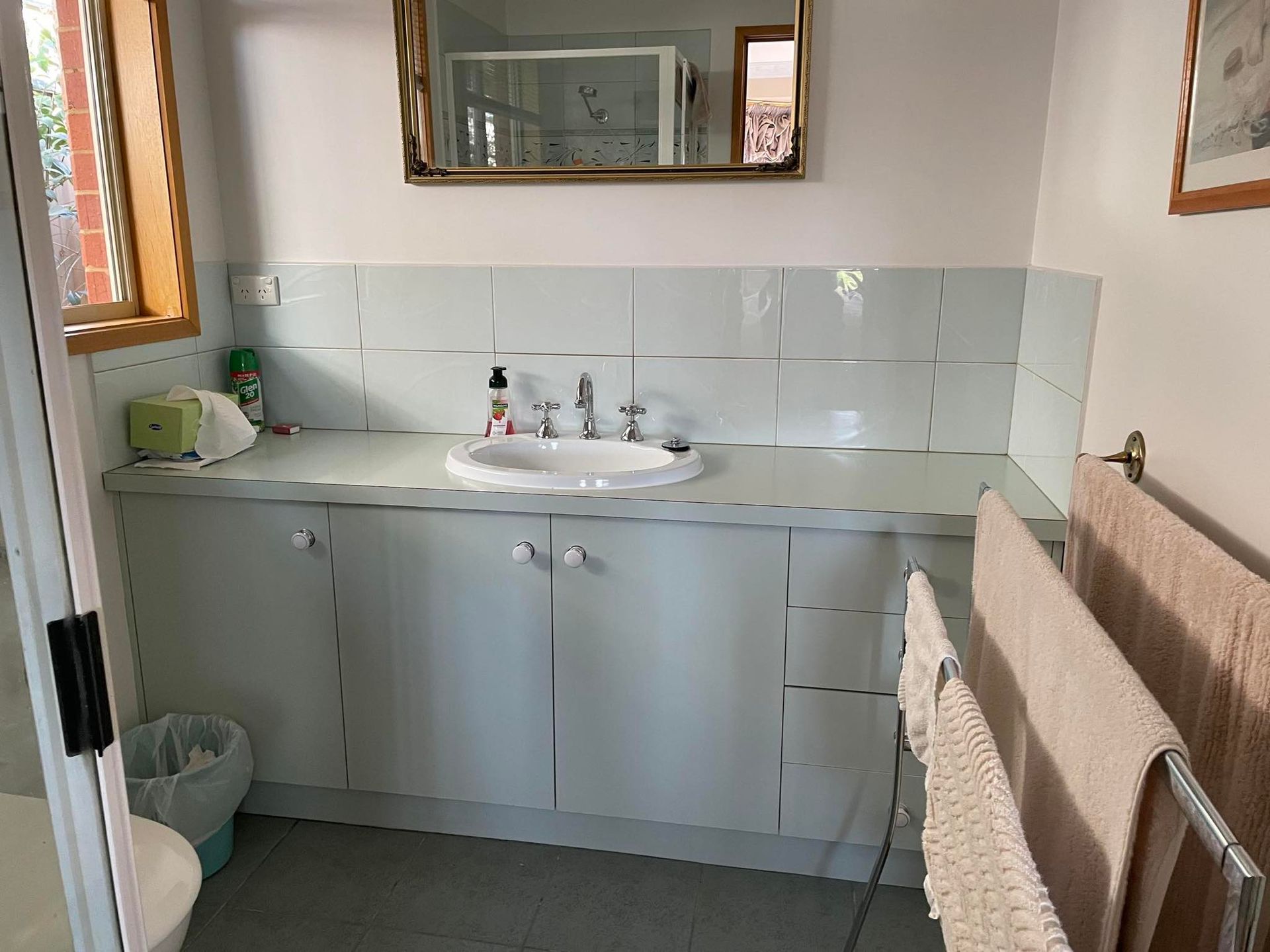 Bathroom with a white vanity, sink, and tiled backsplash; towels hang on a rack.