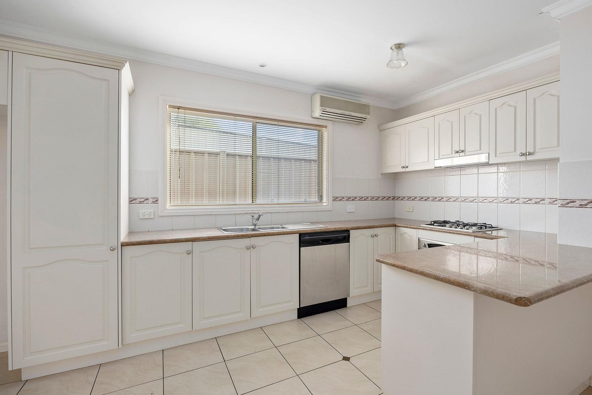 White kitchen with cabinets, a window, stainless steel appliances, and a breakfast bar.
