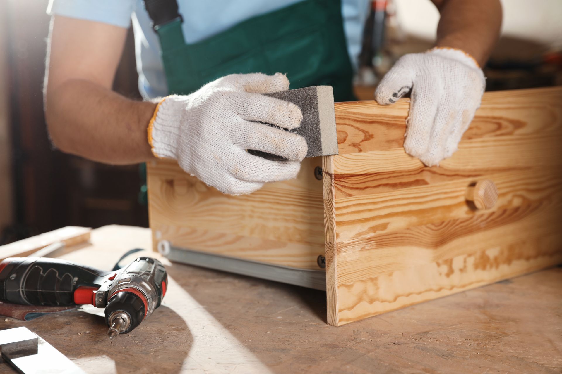 Close-up of a cabinet maker polishing a wooden cabinet in a workshop.