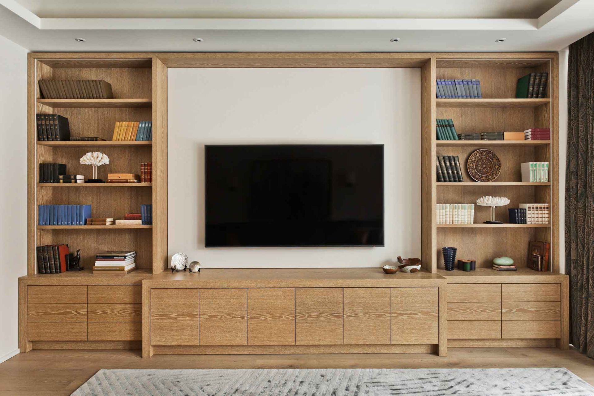 Built-in oak entertainment center with a mounted TV and shelves filled with decorative items.