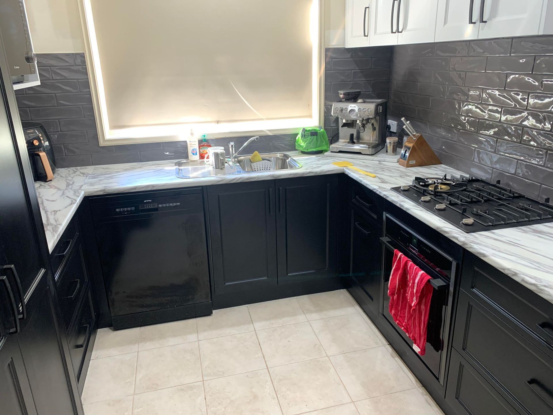 A newly renovated kitchen with white cabinets, stainless steel appliances, light countertops, and wood-look flooring.