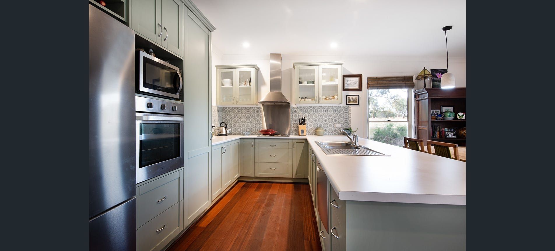 Modern kitchen with white cabinetry, dark countertops, stainless steel appliances, and a dining table.