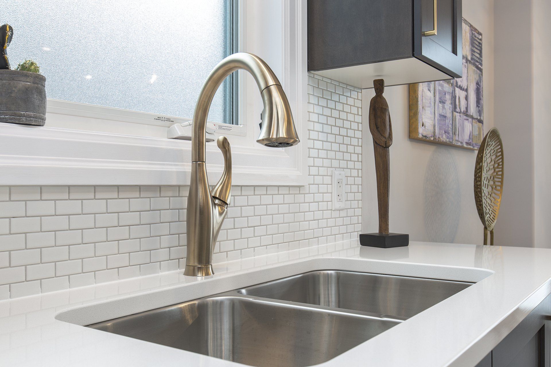 A kitchen sink with two stainless steel sinks and a gold faucet.