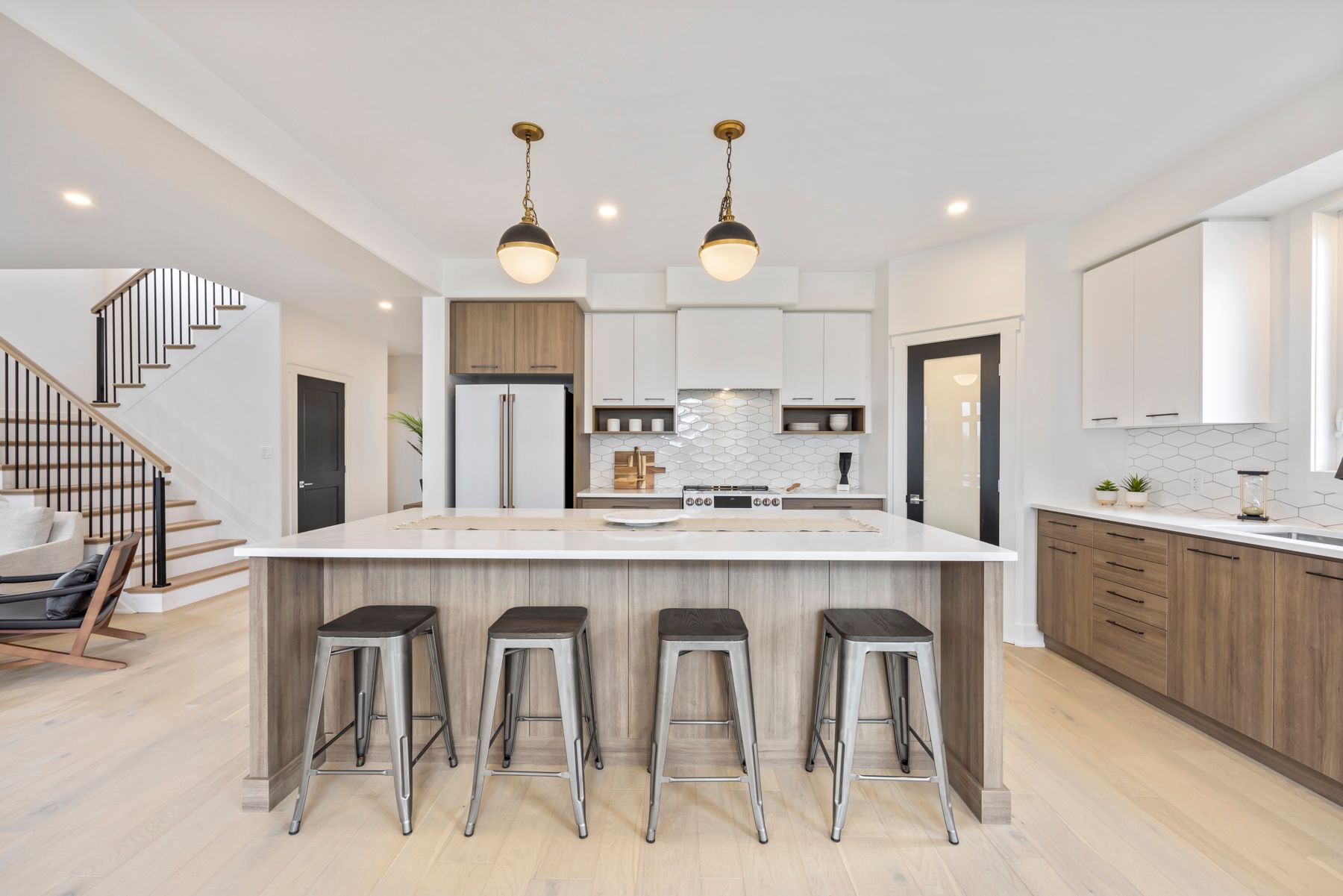 A kitchen with a large island and stools in it.