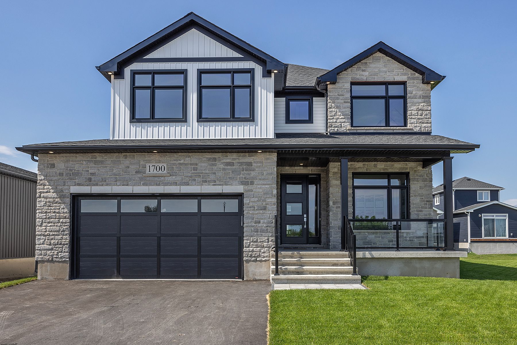 A large house with a black garage door and a lot of windows.