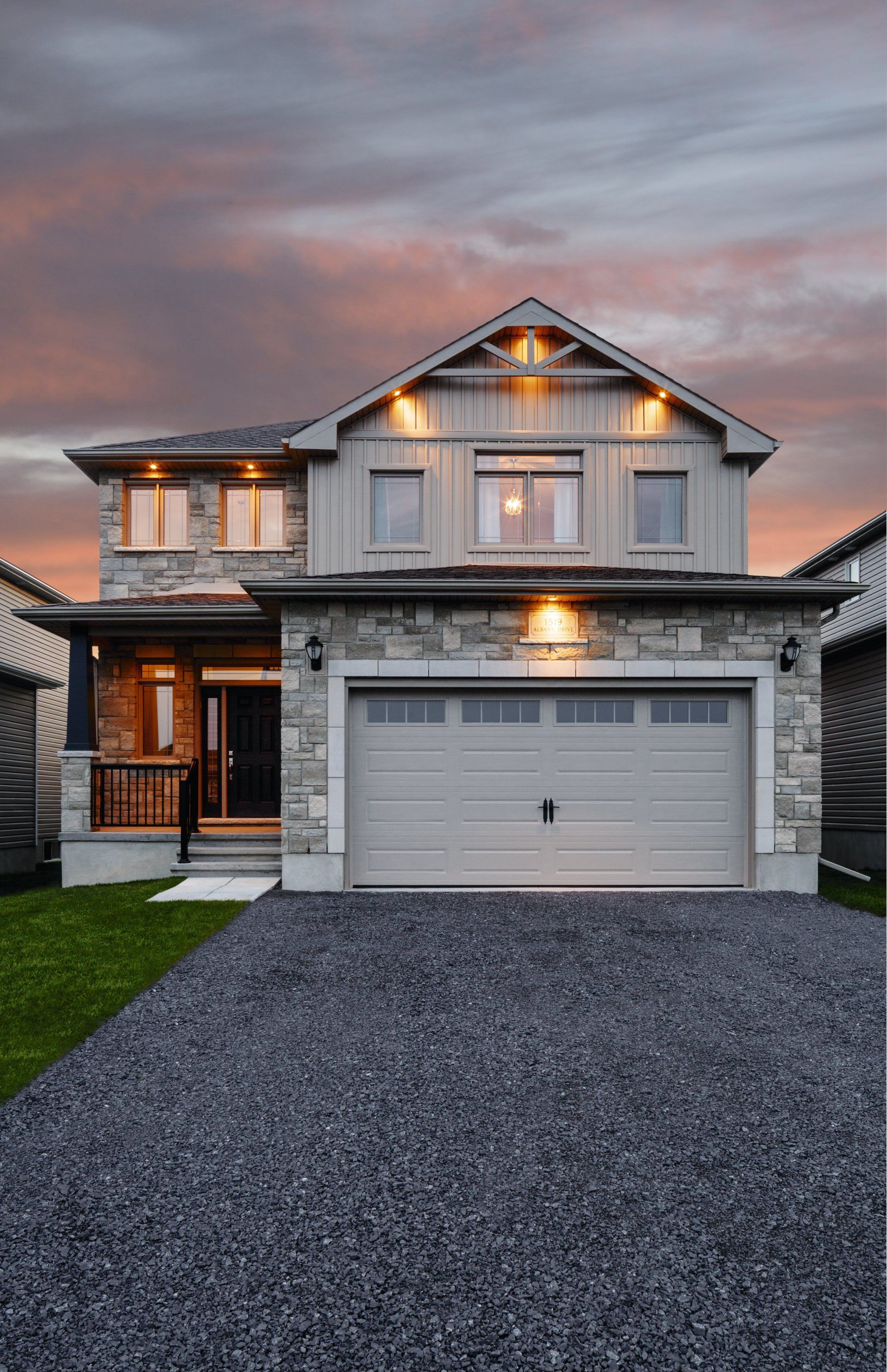 A large house with a garage and driveway at sunset.
