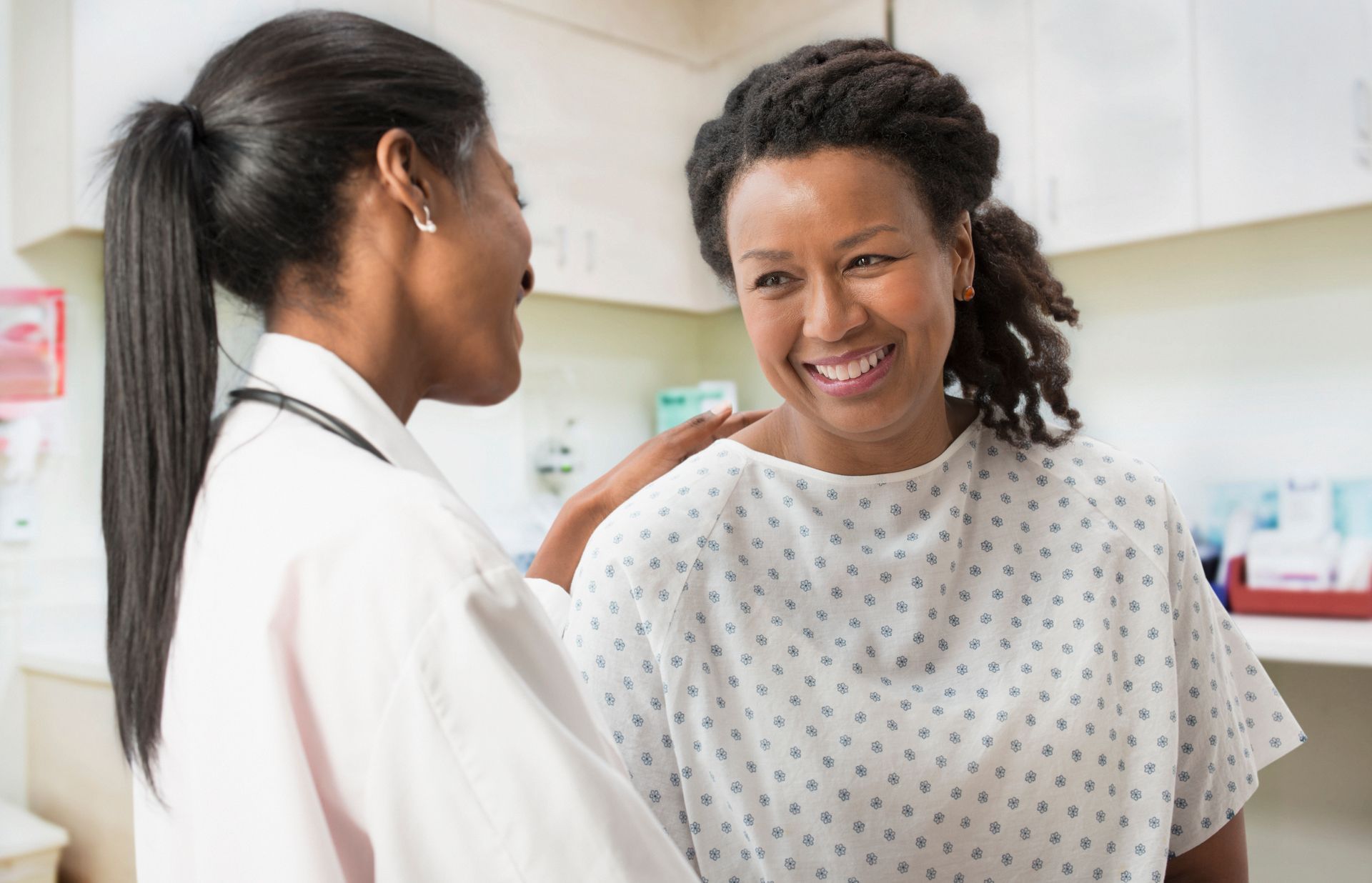 A doctor is talking to a patient in a hospital gown.