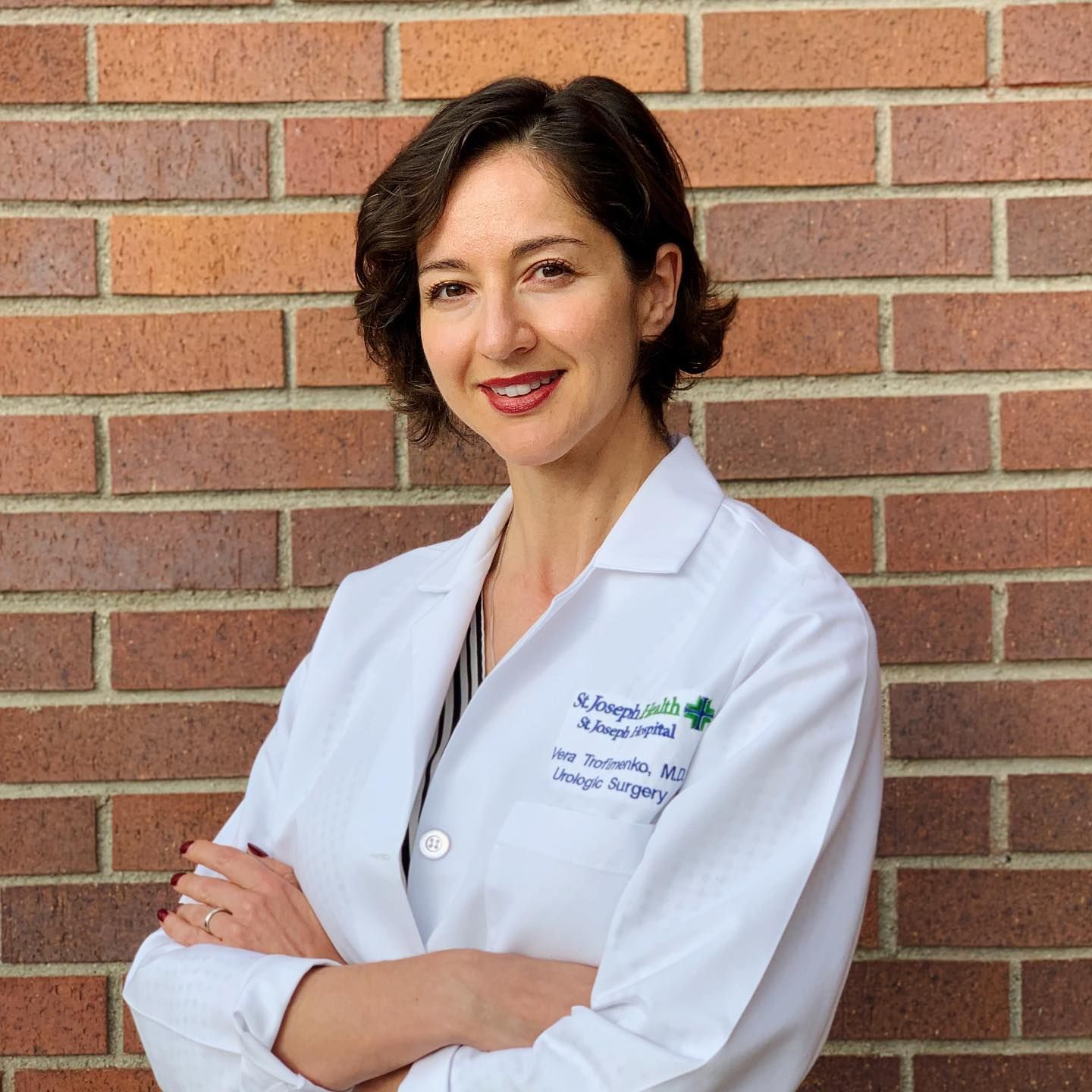 A woman in a white lab coat is smiling and looking at the camera.