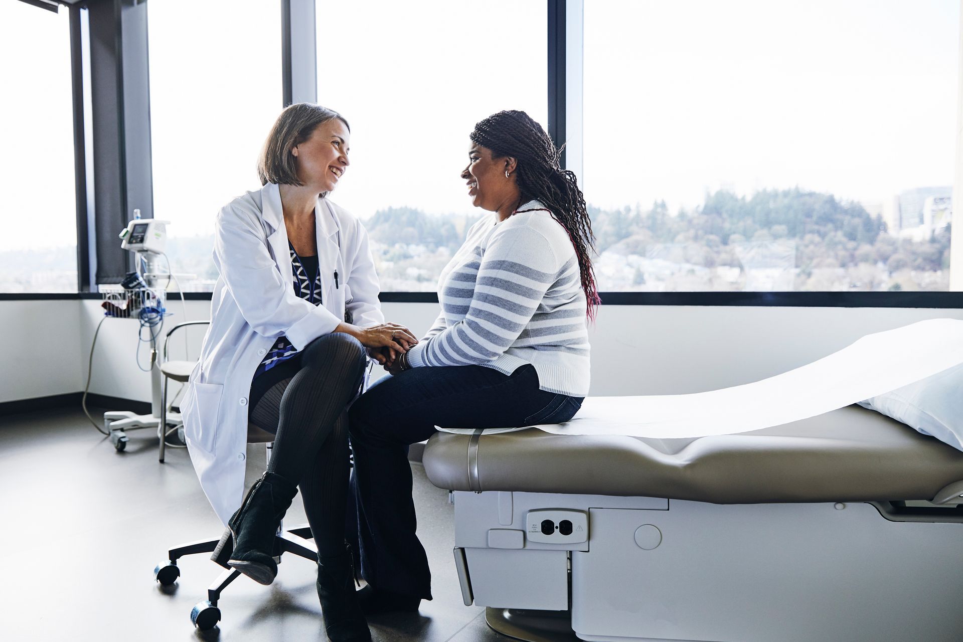 A doctor is talking to a patient who is sitting on a bed.