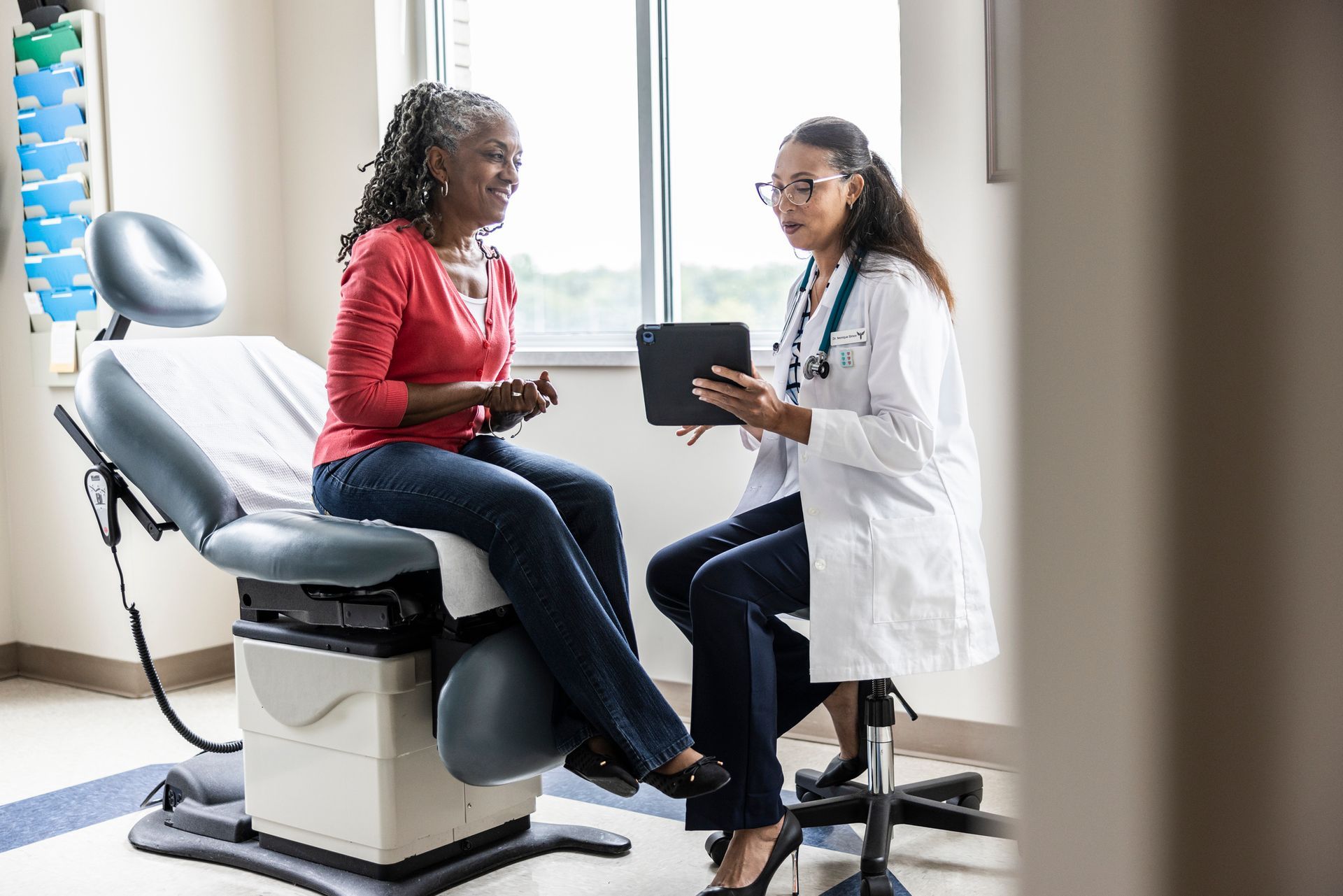 A doctor is talking to a patient who is sitting in an examination chair.