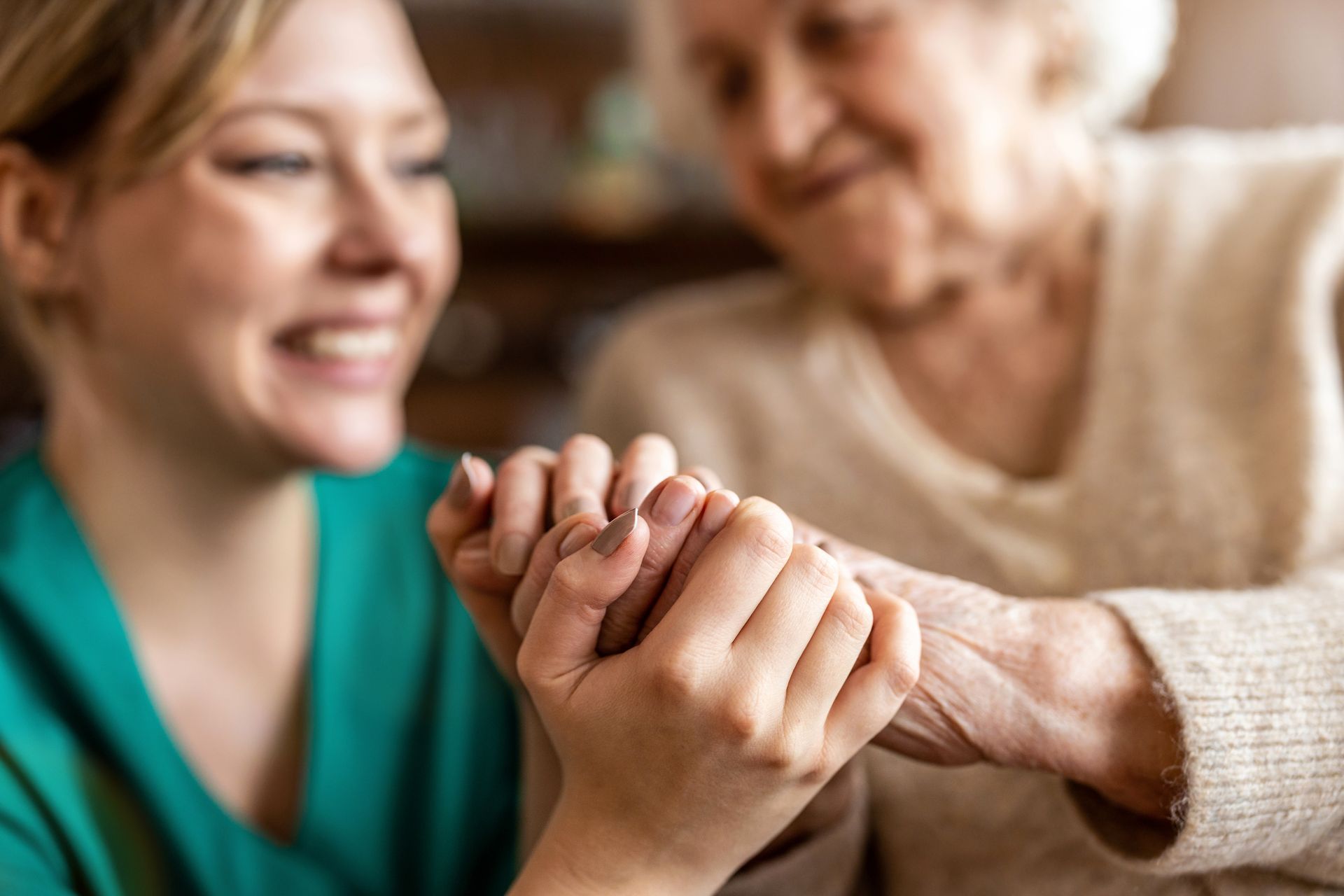 Two people holding hands and smiling during a warm, intimate moment indoors