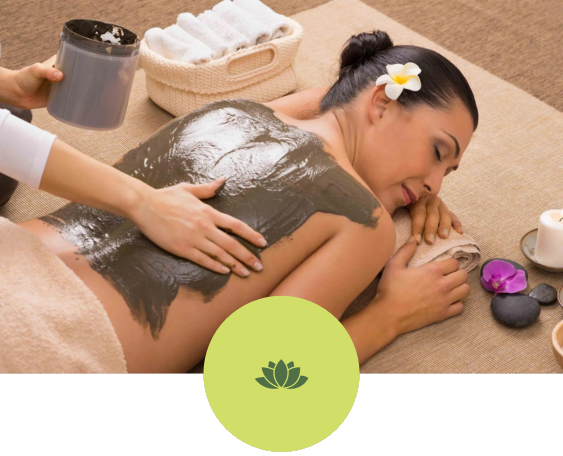 A woman is getting a mud treatment at a spa