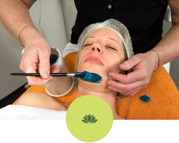 A woman is getting a facial treatment with a brush