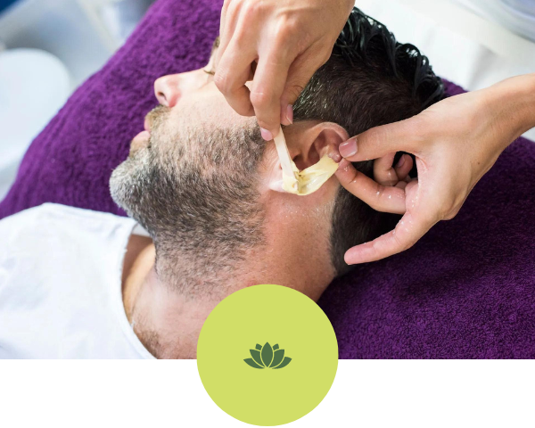 A man is getting his ears waxed at a spa