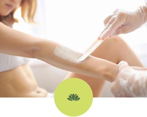 A woman is getting her arm waxed by a person wearing gloves