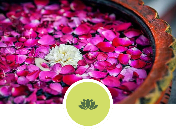 A bowl filled with pink and red flower petals and a lotus symbol