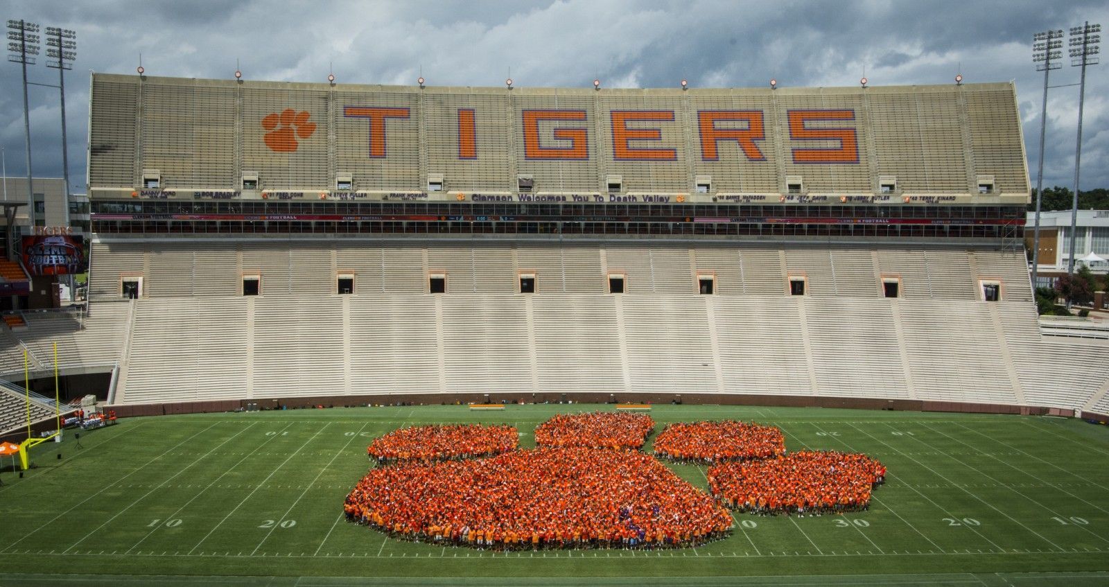 A large group of people are standing in front of a tigers stadium.