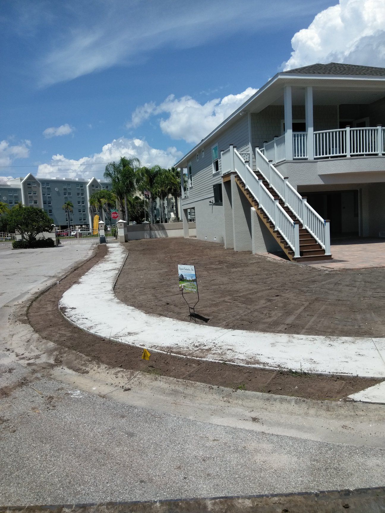 Sidewalk curving past building with stairs; brown mulch and blue sky. Sidewalk curving past building with stairs; brown mulch and blue sky.