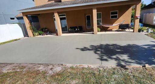 Newly poured concrete patio outside a brown house.