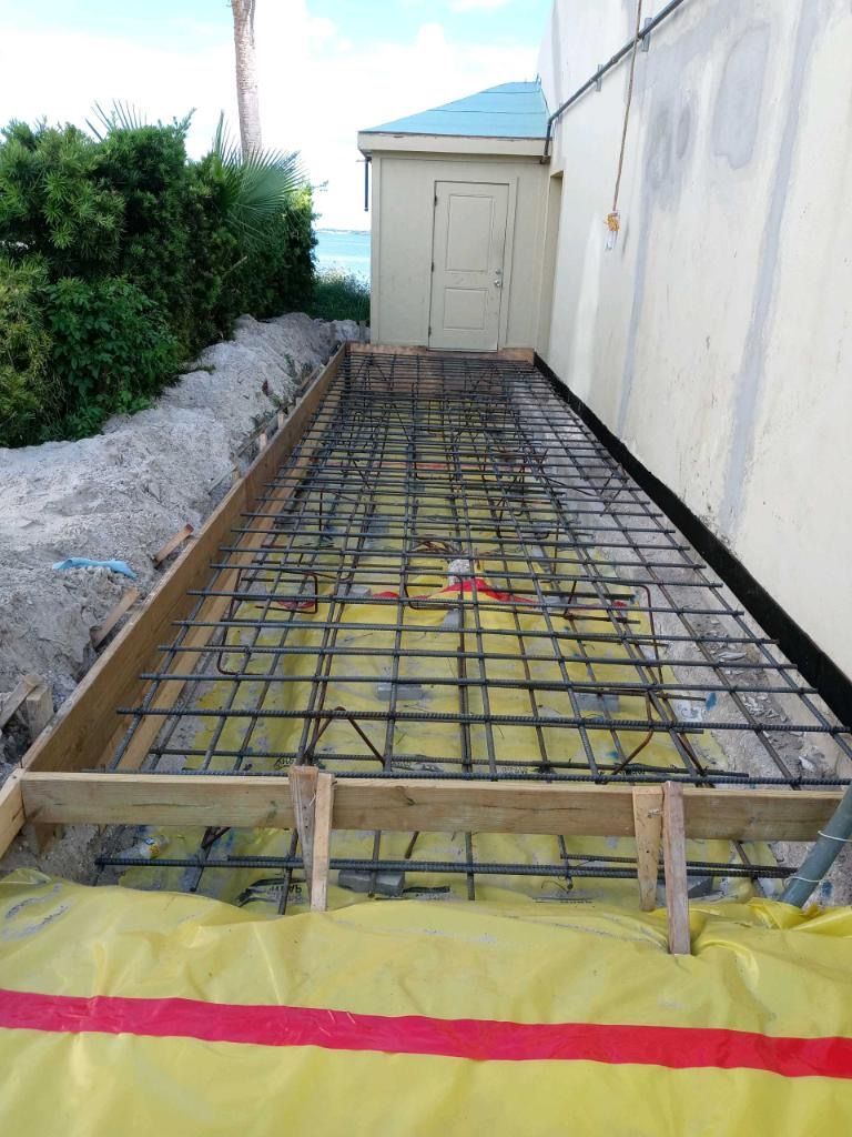 Wooden forms with rebar grid laid on yellow sheeting, ready for concrete slab pour next to building. Wooden forms with rebar grid laid on yellow sheeting, ready for concrete slab pour next to building.