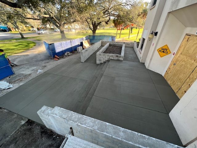 New concrete patio outside a building. Construction in progress, with a blue dumpster visible. New concrete patio outside a building. Construction in progress, with a blue dumpster visible.
