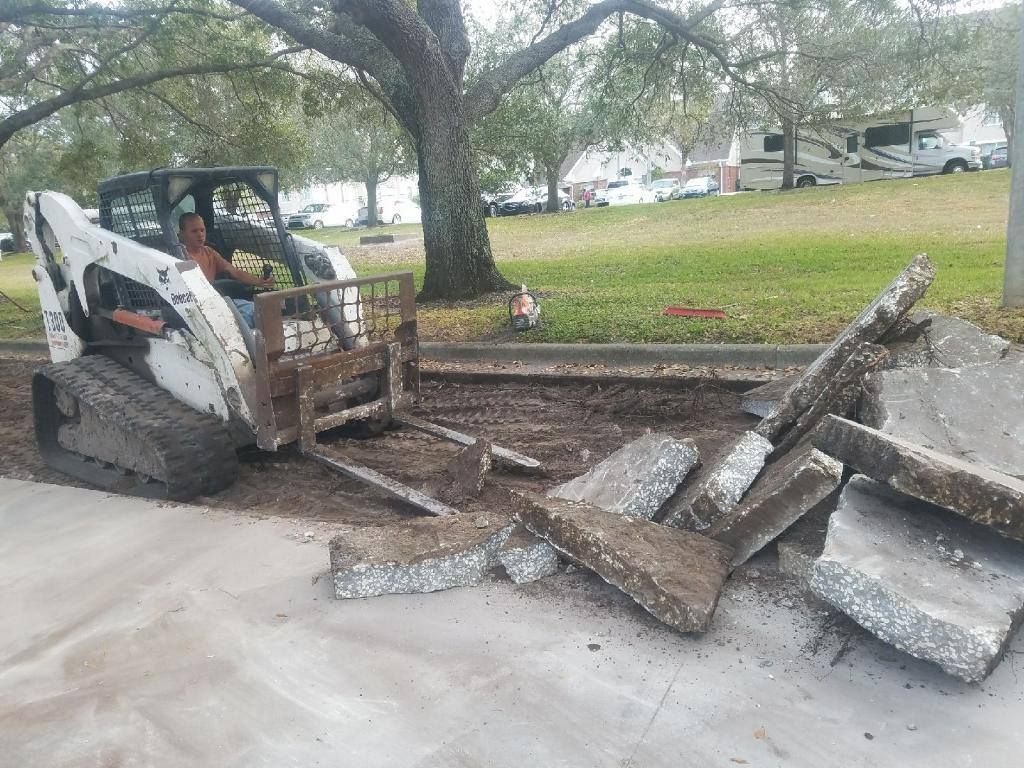 Road construction site: orange loader next to piles of broken asphalt on a street.