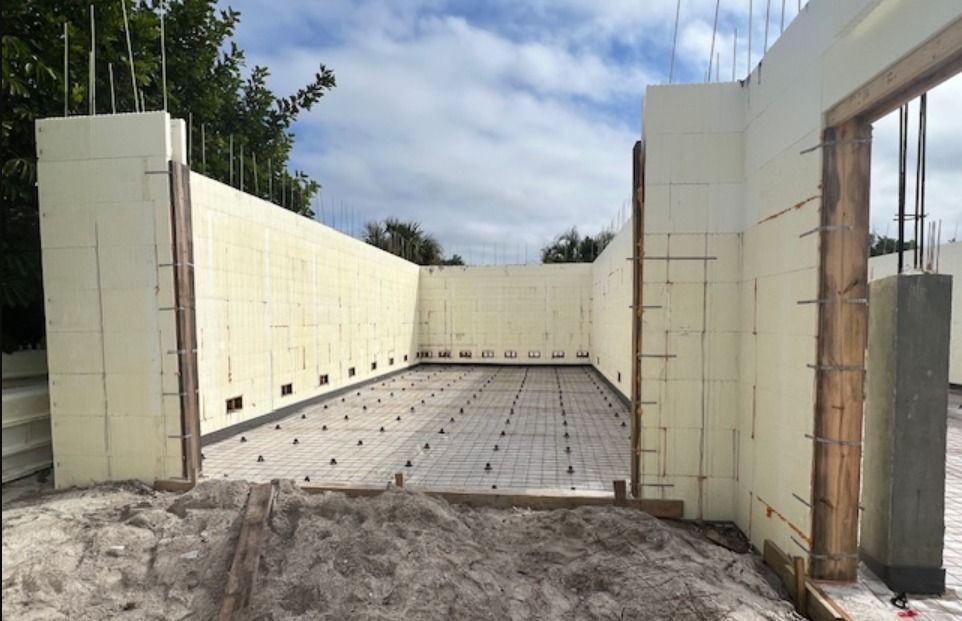 Exterior view of a building under construction, showing insulated concrete forms. Rebar and wooden door frame visible. Exterior view of a building under construction, showing insulated concrete forms. Rebar and wooden door frame visible.