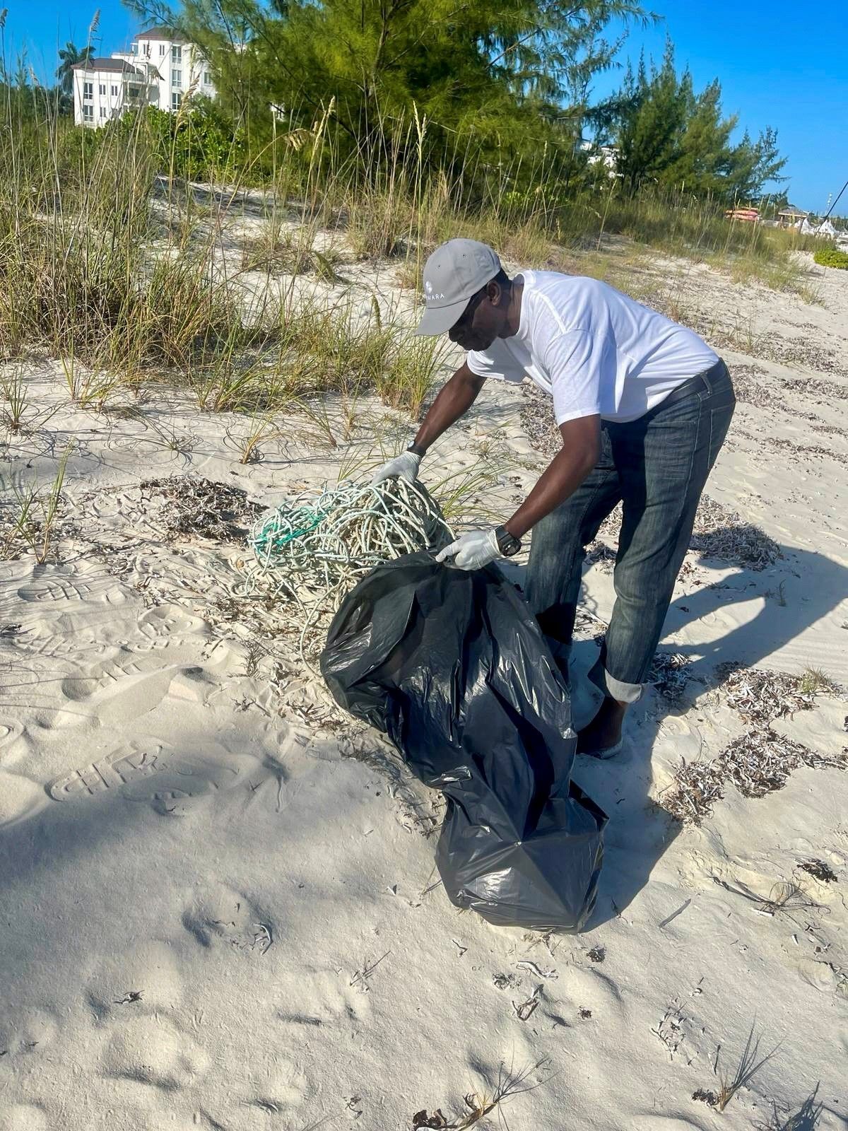 A man is picking up trash on a beach.