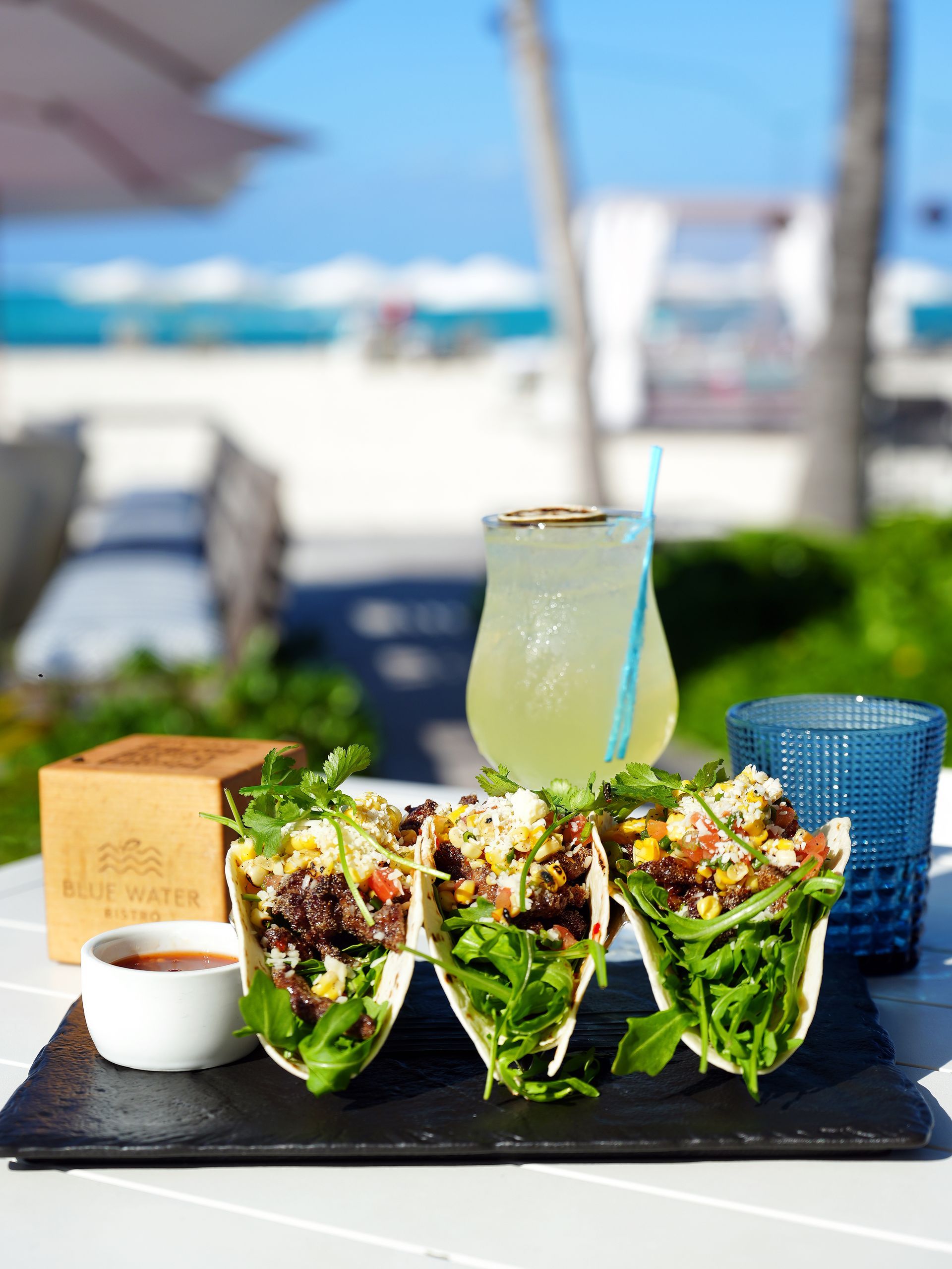 A table on the beach with a bottle of wine on it