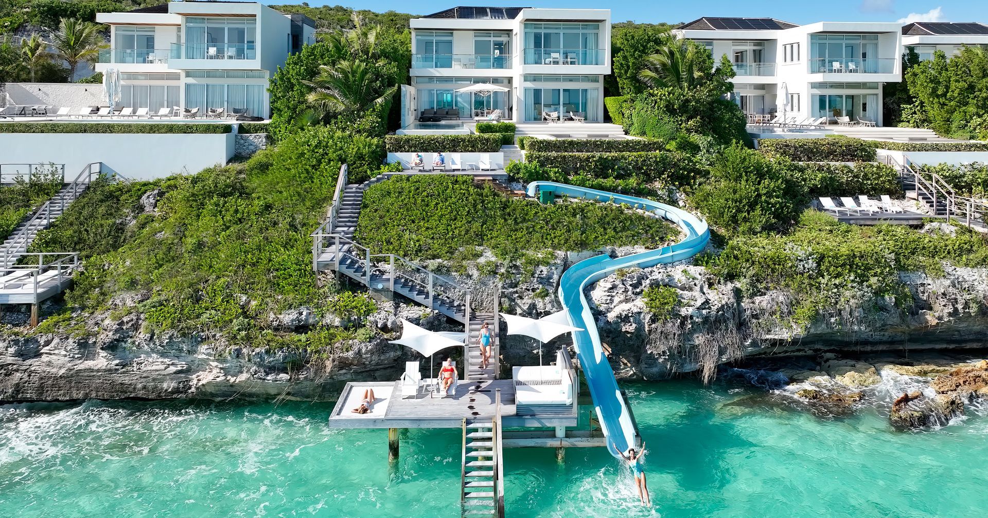 An aerial view of a resort with a water slide and a dock